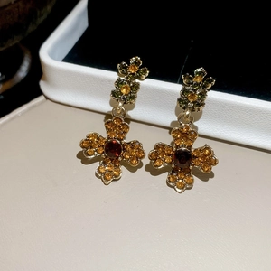 Detailed shot of vintage gold floral cross earrings with amber and red rhinestones