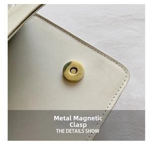 Detail shot of the golden magnetic snap and leather texture on the ivory handbag