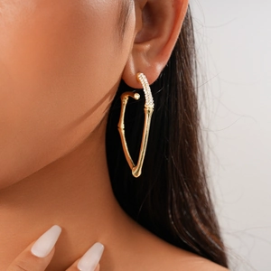 Close-up of a gold-plated bamboo-shaped earring with sparkling crystal accents