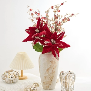 Fleur de poinsettia rouge artificielle avec paillettes d'or dans un vase beige