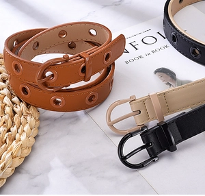 Detail view of colorful PU leather belts with metal buckles on a marble surface