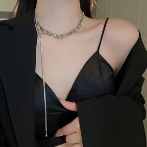 Detail of silver leaf sequin snake tassel necklace worn by a model in black outfit