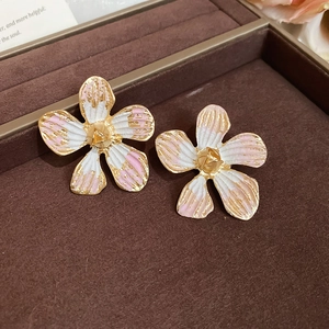 Macro view of flower stud earrings featuring white and pink enamel petals with gold finish