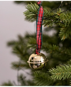 Close-up of golden Christmas bells with red and green plaid ribbon on a green pine tree