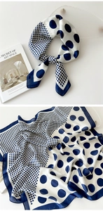Detail of silk-like satin square scarf with blue and white polka dots on an art book