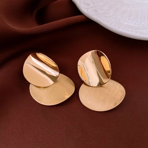 Detail view of gold geometric flower earrings with polished and brushed metal textures