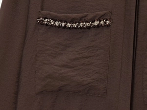 Detail of deep brown blouse pocket with textured tweed woven trim and fine fabric weave