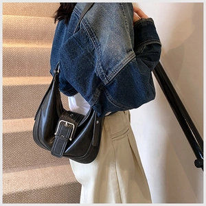 Detailansicht einer schwarzen Leder-Halbmondtasche mit Silberschnalle an einem Model