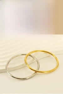 Detail of minimalist gold and silver stainless steel oval bangles with smooth finish
