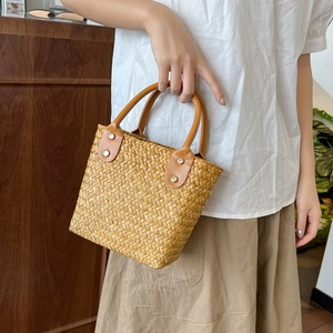 Close-up of woven straw texture and handle detail on a stylish summer handbag
