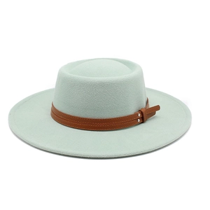 Detail of mint green wool felt boater hat with brown leather straps and silver buckles