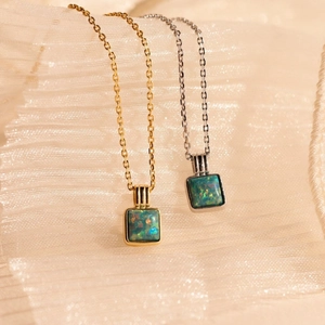 Elegant gold and silver square opal pendant necklaces on soft silk fabric display