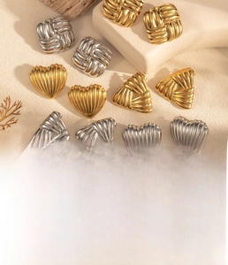 Detailed view of geometric heart and square earrings with pleated metal texture in gold