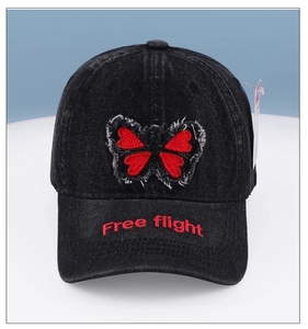 Detail of black denim baseball cap with red butterfly patch and Free flight embroidery