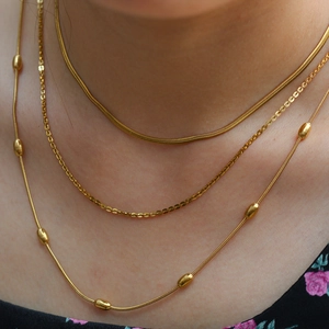 Collana doppia a serpente dorata con piccole perline e ciondoli a disco minimalisti