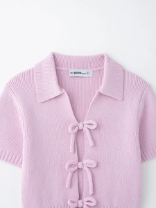 Detailed view of pink rib-knit short sleeve top featuring front bow tie closures and V-neck