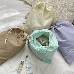 Waterproof drawstring bags in four colors for travel storage on white bedding detail