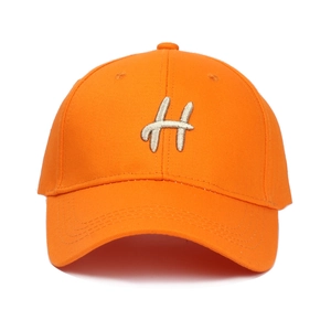 Vue détaillée d'une casquette orange vif avec broderie blanche de la lettre H et coutures