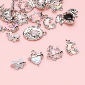 Silver alloy charms set with moon butterfly and heart crystals on pink background