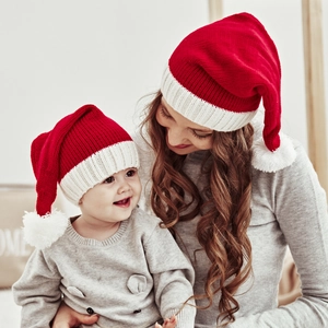 Close-up of mother and baby wearing red and white knitted Christmas pompom hats