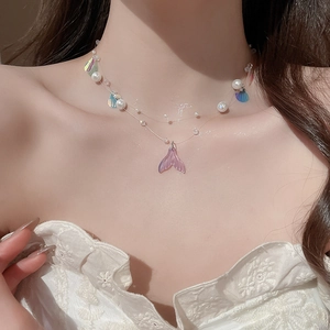 Detail of double-layer fishtail necklace with pearls and shells on lace collar