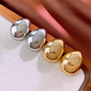 Boucles d'oreilles gouttes polies en or et argent sur tissu et plateau en bois