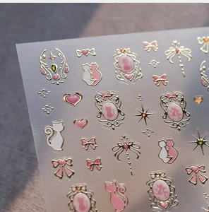Détail de stickers à ongles chat rose avec bordures dorées et motifs de nœuds