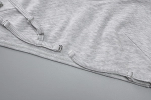 Detail of light grey ribbed knit crop top featuring adjustable metal strap buckles