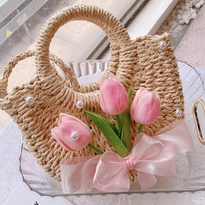 Close-up of woven straw bag featuring pink tulips, silk bows and pearl details
