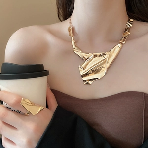 Close-up of golden irregular textured necklace and ring set with liquid metal effect
