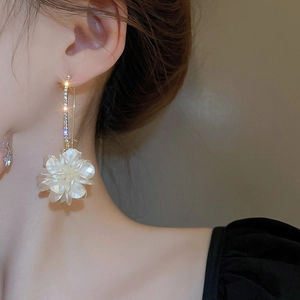 Gros plan d'élégantes boucles d'oreilles pendantes à fleurs blanches et strass brillants