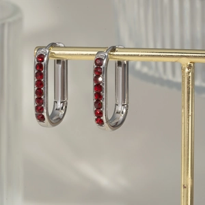 U-shaped silver earrings with red round gemstones displayed on a golden metal jewelry stand