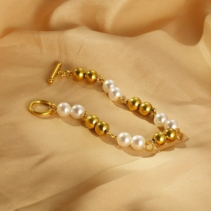 Detail of pearl and gold bead bracelet with OT clasp on luxury warm silk background