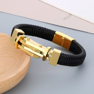 Primo piano del bracciale in pelle nera intrecciata con chiusura in metallo dorato lucido
