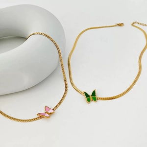 Detail of pink and emerald green butterfly pendants on flat golden herringbone chains