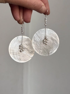 Detail of round shell disk earrings with hanging freshwater pearls and silver tassels