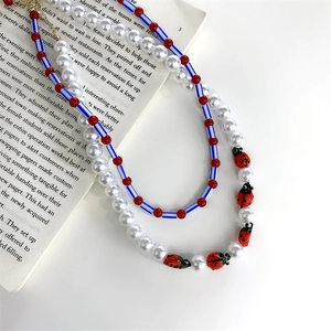 Double-layered beaded necklace with pearls and ladybug charms on a vintage book