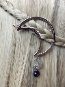 Detail of silver moon hair clip with purple beads styled on golden braided hair