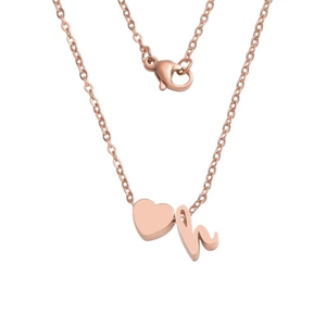 Close-up of rose gold necklace featuring a polished heart charm and cursive letter h pendant