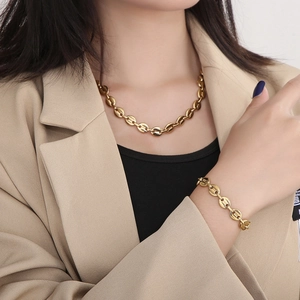 Close-up of gold oval pig nose link necklace and bracelet set on a professional model
