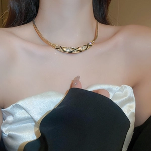 Close-up of vintage style gold necklace with curved enamel and sparkling rhinestones