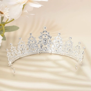Close-up of luxury silver hollowed crown with sparkling rhinestones on silk background