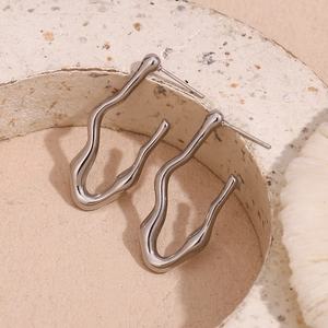 Macro shot of silver liquid metal earrings with polished wave design in ceramic bowl