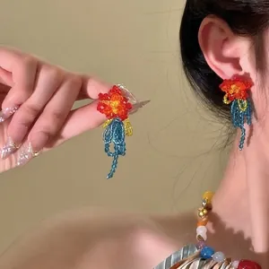 Close-up of bohemian beaded tassel earrings with colorful floral design on model