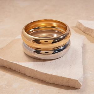 Close-up of thick gold and silver chunky bangles on textured natural stone