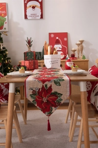 Dettaglio del runner da tavola natalizio con nappe rosse e decorazioni a stella di Natale