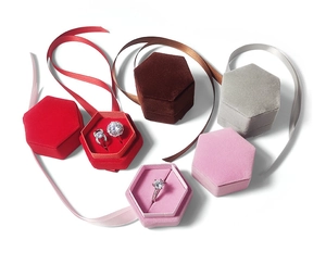Flat lay of colorful hexagonal velvet jewelry boxes with silk ribbons and ring slots