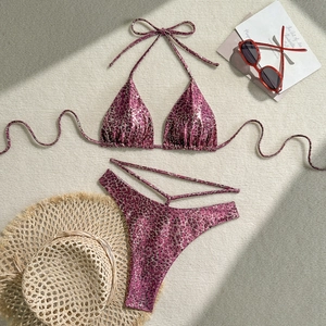 Flat lay of pink leopard bikini with metallic finish on a woven beach mat