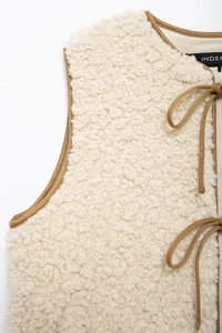 Detail of soft fleece vest with contrast camel trim and lace-up neck closure