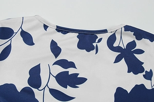 Detaillierte Nahaufnahme des Rundhalsausschnitts und blauen Blumenmusters auf weißem Sommerkleid